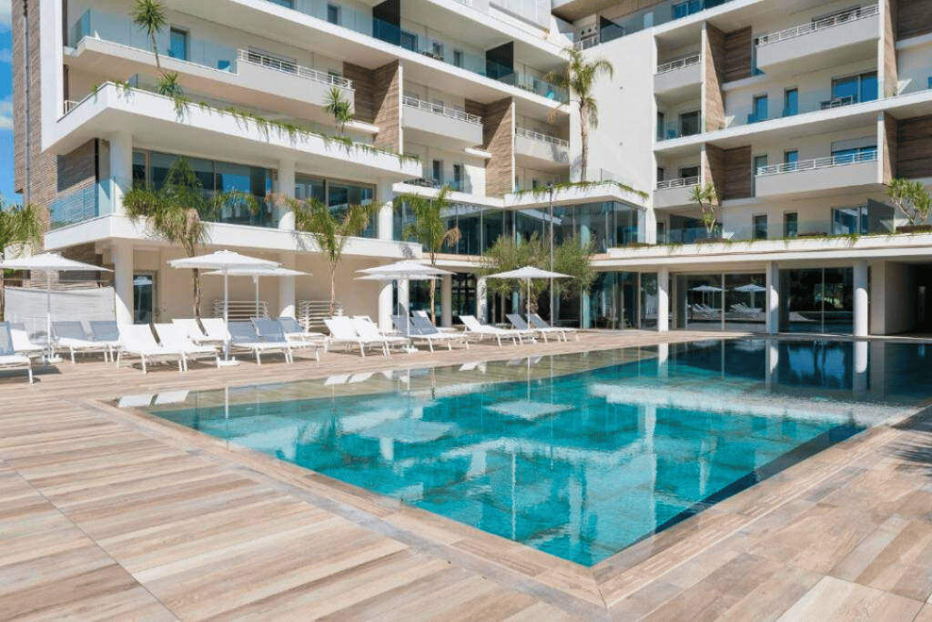 Ein Hotel helles, modernes Hotel mit Liegen und Schirmen an einem Pool