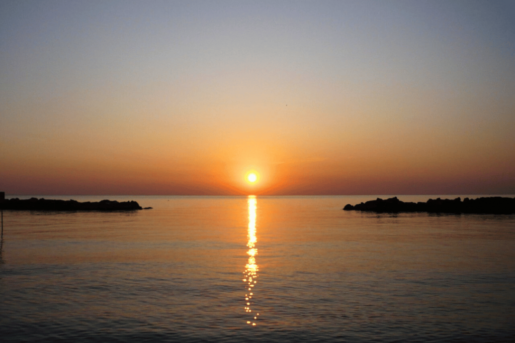 Eine orangefarbene Sonne steigt aus dem Meer in Martinsicuro