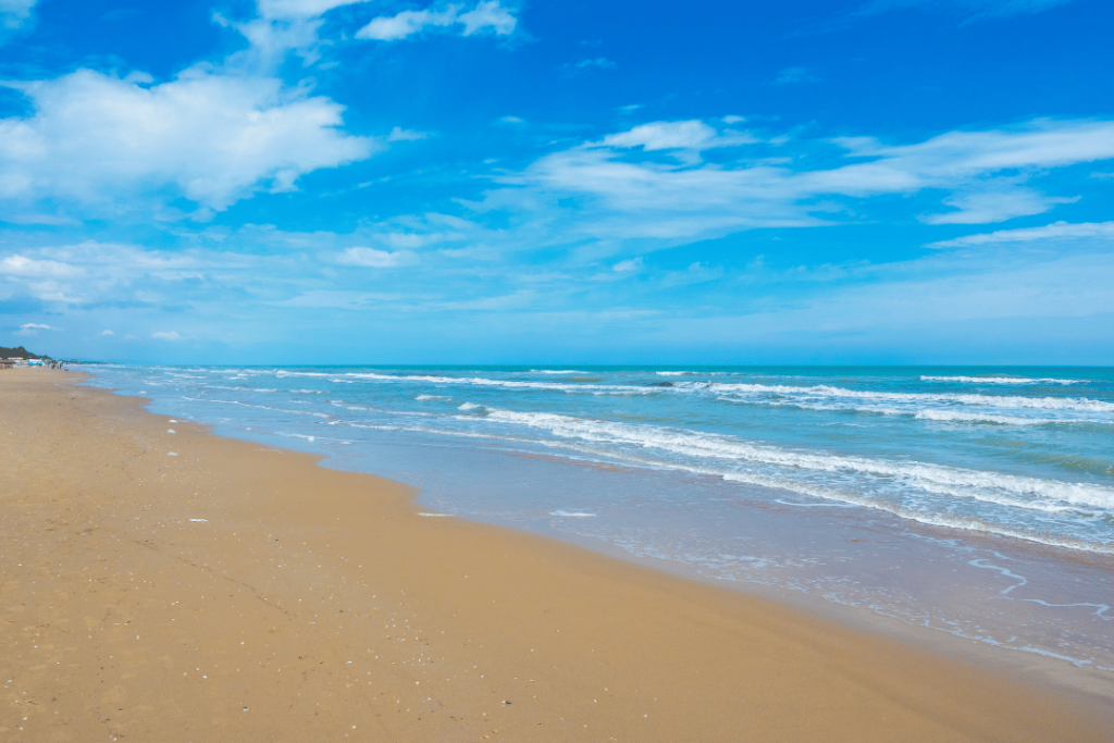 Ein weitläufiger Sandstrand mit seichtem blauen Meerwasser