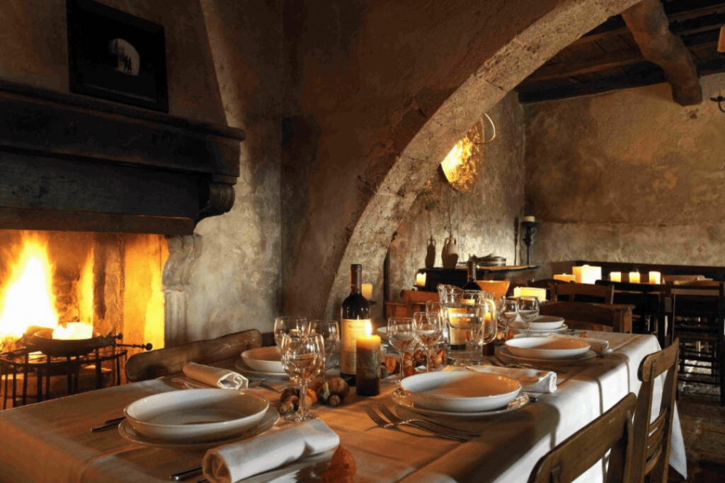 Eine reich gedeckte Tafel vor Kaminfeuer und Kerzenschein im Sextantio Albergo Diffuso