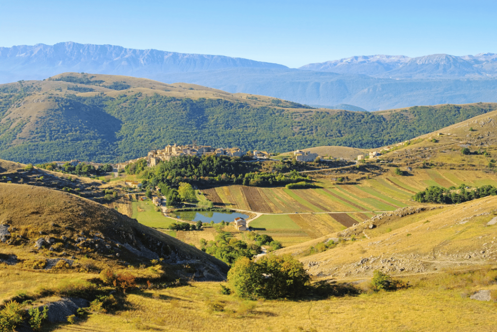 Blick auf einen kleinen See und das Dorf Santo Sessanio vor Bäumen und Bergen