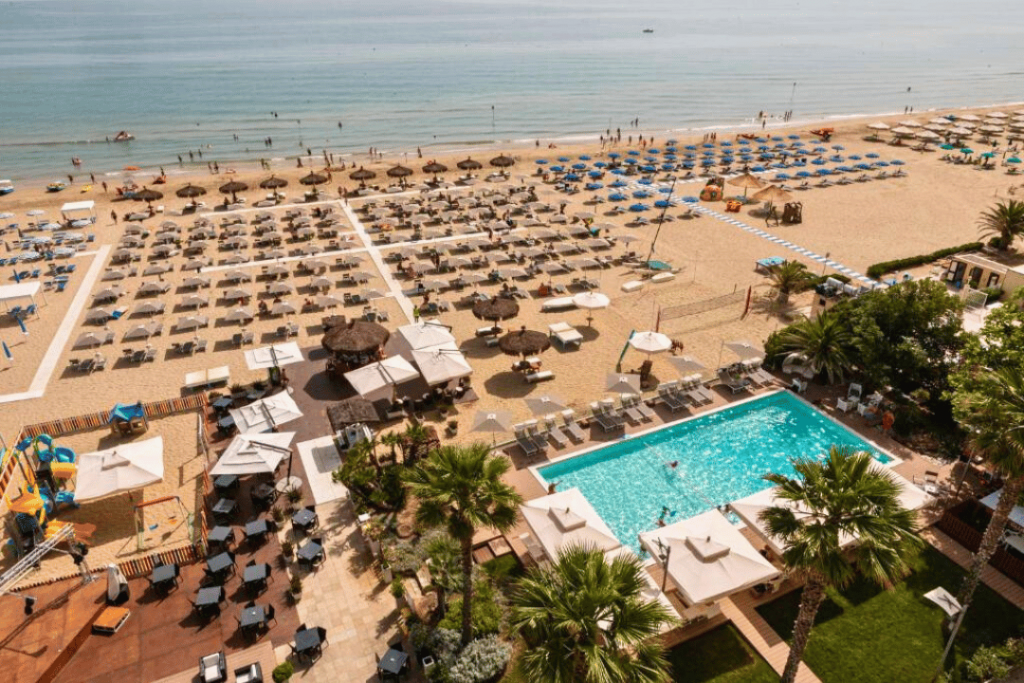 Blick auf einen Swimming Pool und einen Strand mit liegen und Sonnenschirmen